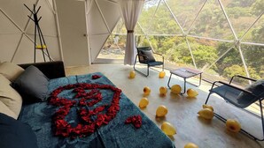 Une pièce spacieuse avec un lit, une chaise et une table. Il y a des ballons par terre.