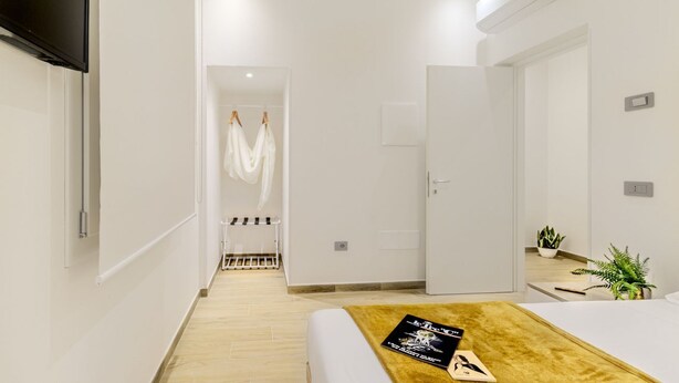 Una habitación de hotel moderna con cama, televisión, armario y baño visible a través de una puerta abierta.