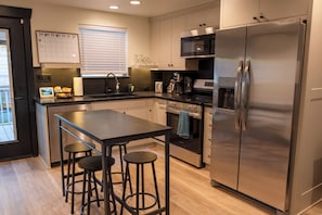 A modern kitchen with a central island, stainless steel appliances, and a calendar on the wall.