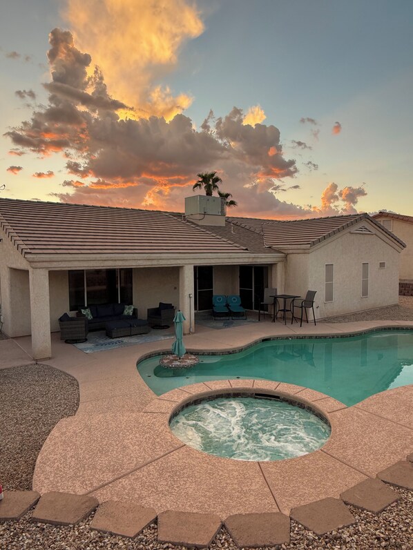 A residential property with a swimming pool, outdoor seating area, and a covered patio.
