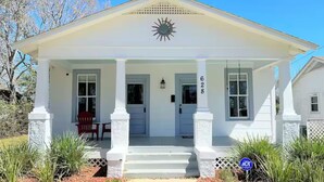 A white building with a front porch, a number '628' on the door, and a sun emblem above the entrance.