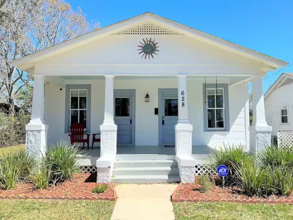 A white building with a porch, a front door, and a mailbox.