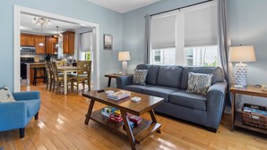 A living room with a sofa, coffee table, and a dining area with chairs and a table.