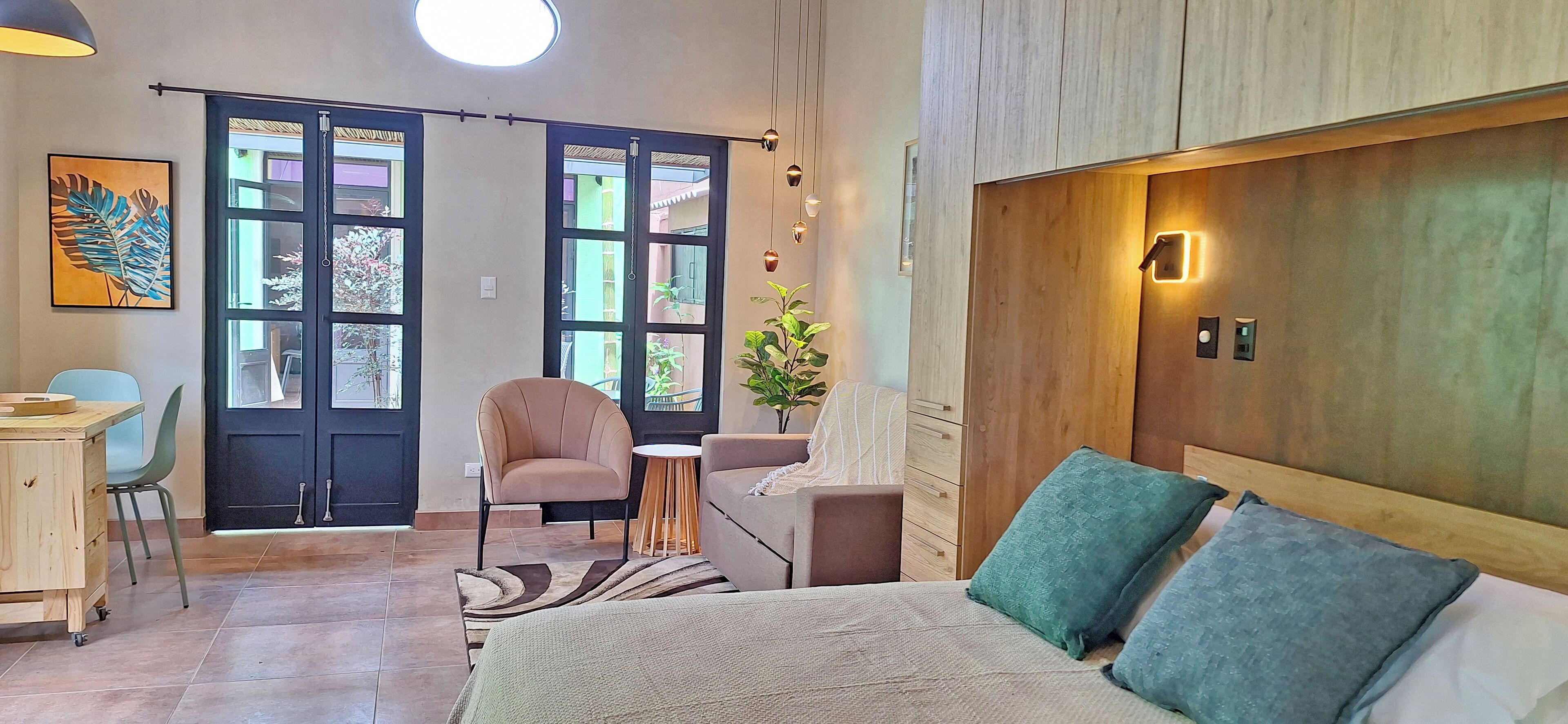A modern bedroom with a bed, a chair, a small table, and a wooden cabinet.