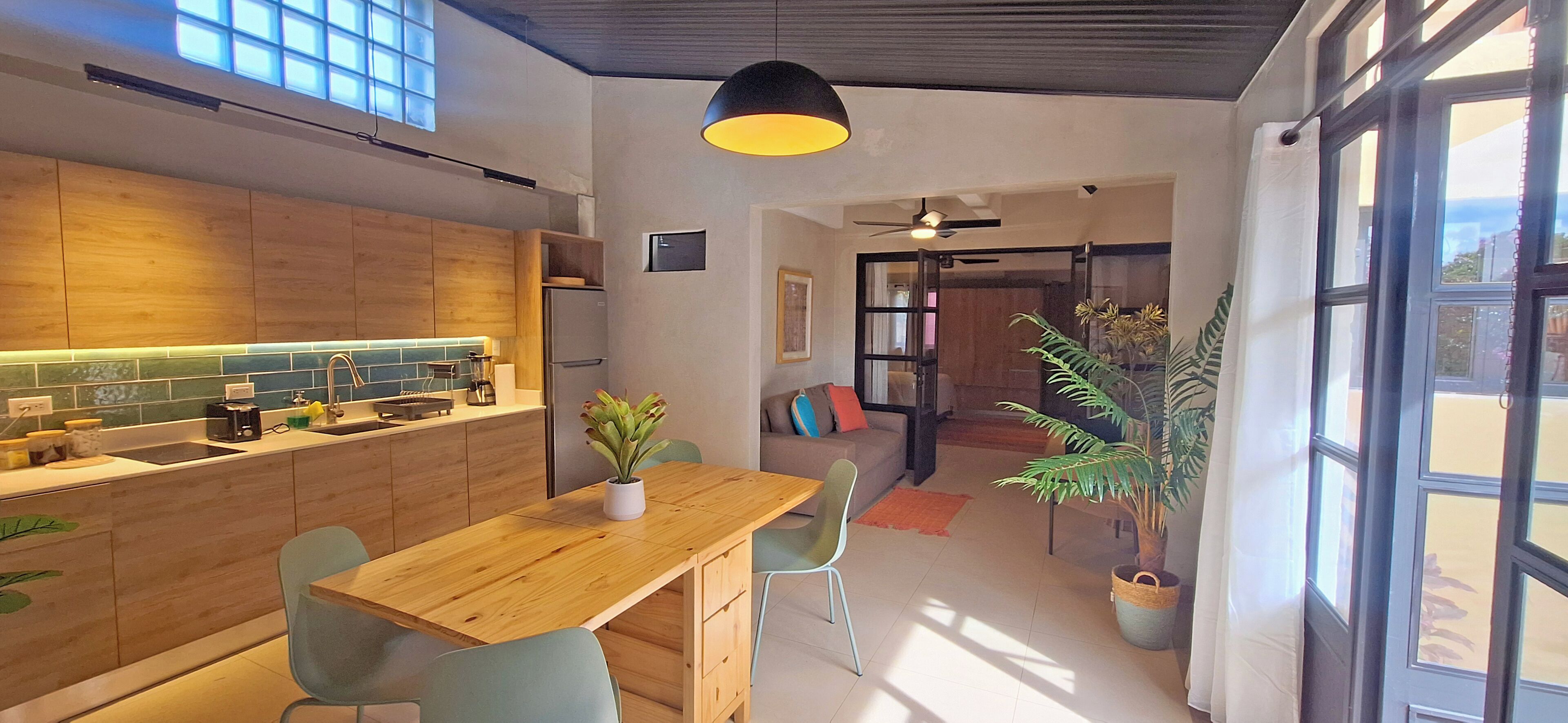 Een moderne keuken met houten kastjes, een ingebouwd eiland en een eethoek met een houten tafel en stoelen.