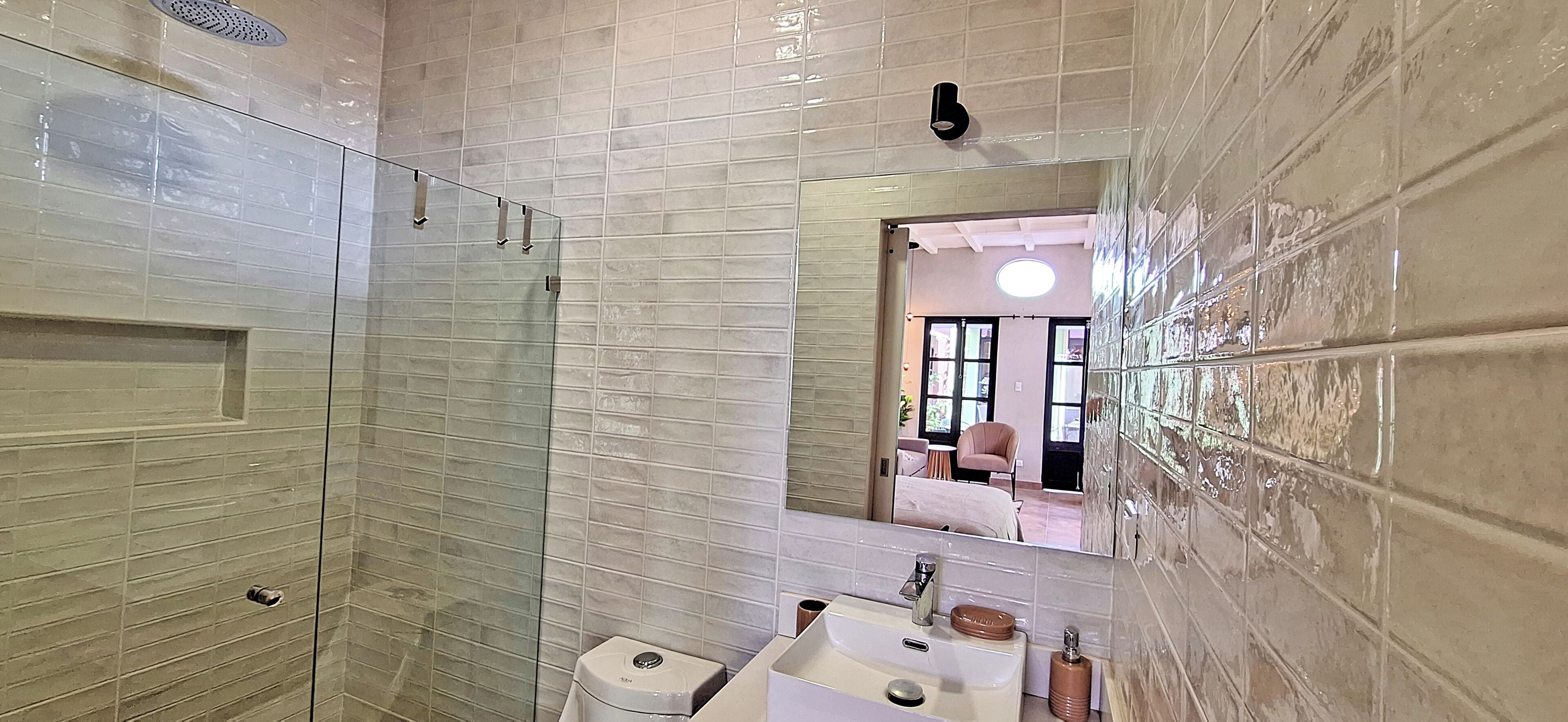 Une salle de bain avec une douche à parois de verre, un lavabo avec un miroir et des toilettes.
