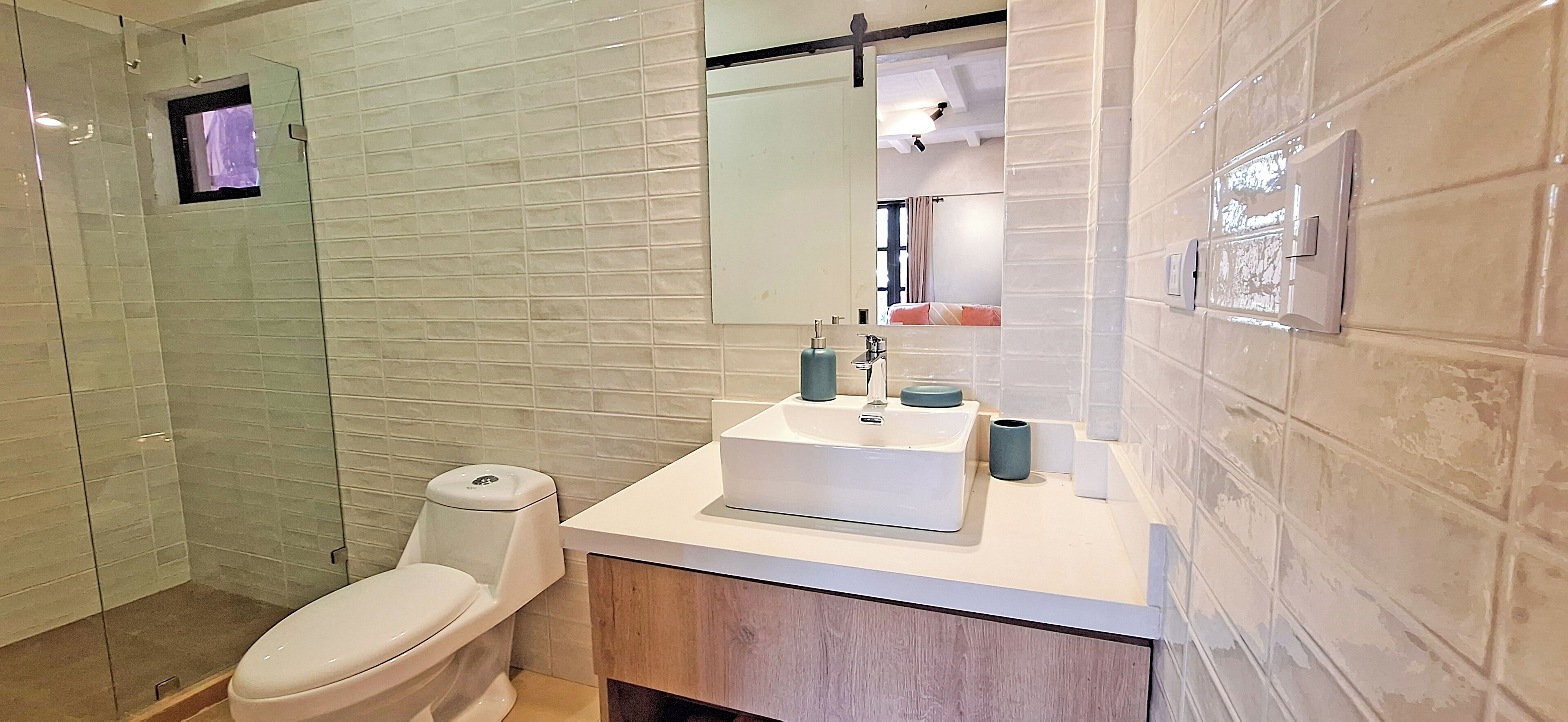 A modern bathroom with a glass shower enclosure, a toilet, a sink with a mirror, and a towel rack.
