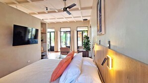 Een moderne hotelkamer met een groot bed, een plafondventilator, een televisie en uitzicht op het omliggende landschap.