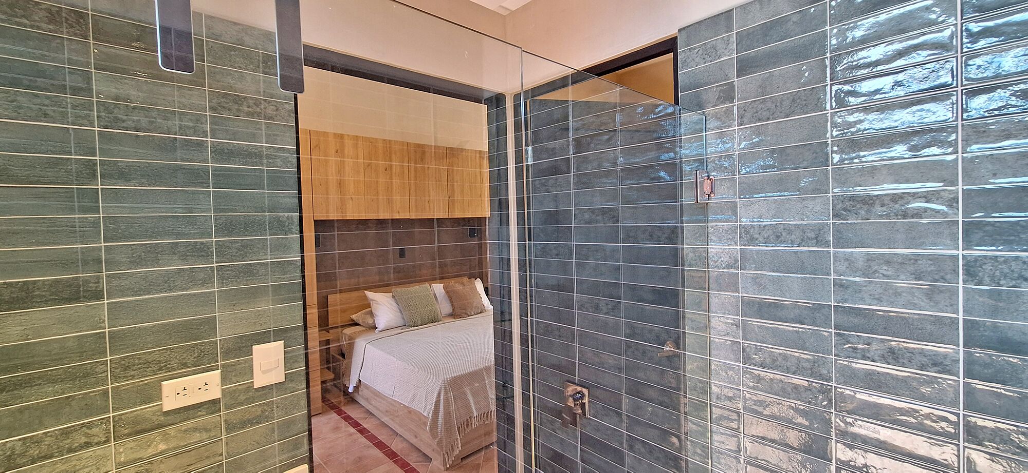 Ein modernes Schlafzimmer mit Bett, Holz-Kopfteil und Glastrennwand.