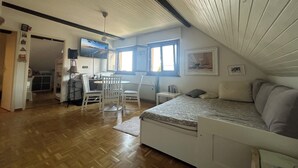 A cozy attic bedroom with a bed, a small table, and a window. - Cosy studio with views of Lake Geneva and Mont Blanc (Arzier-Le Muids)