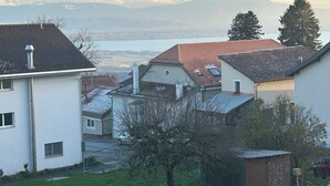 A residential area with houses, a small building, and a view of mountains and a lake. - Cosy studio with views of Lake Geneva and Mont Blanc (Arzier-Le Muids)