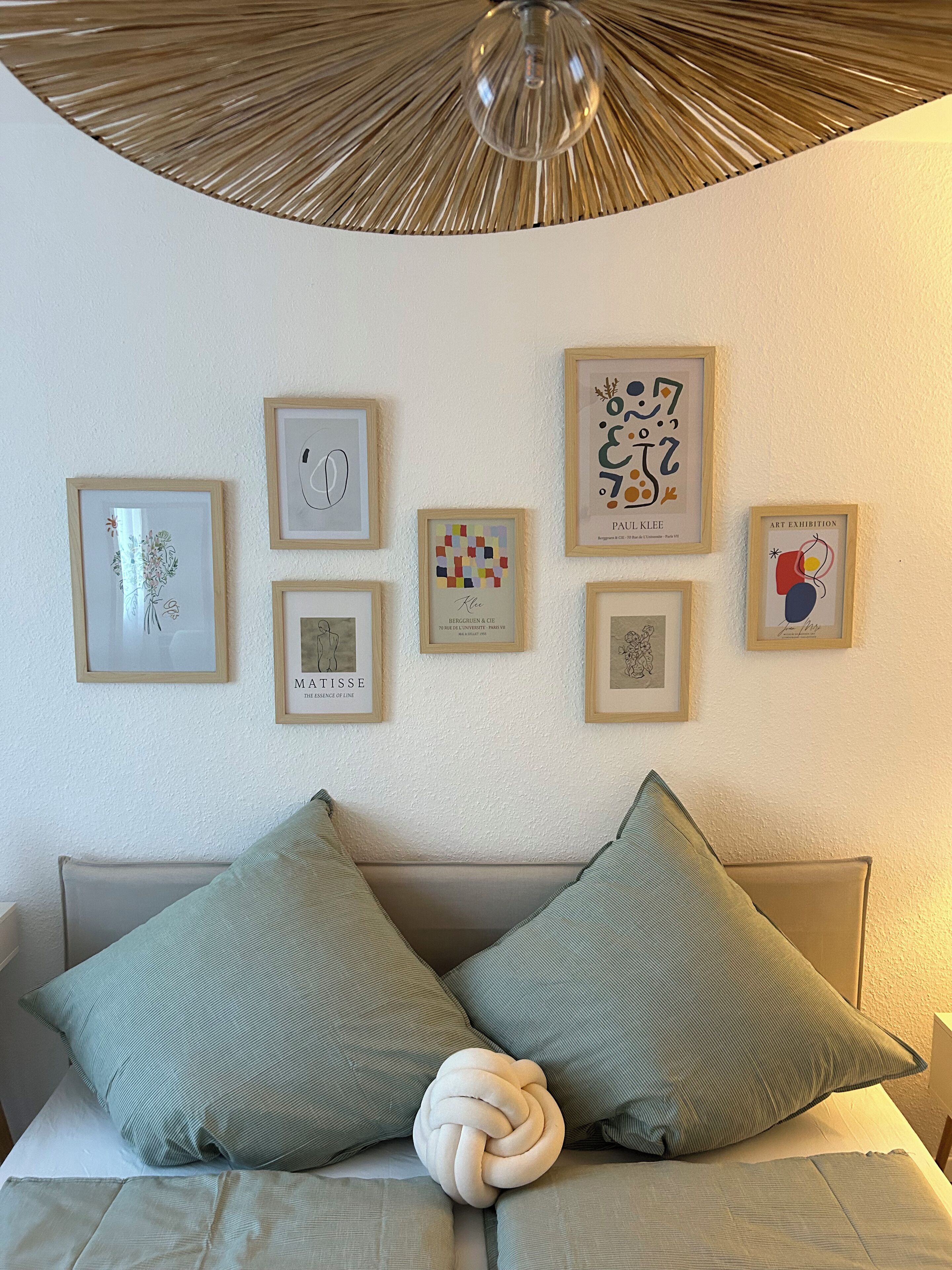Un dormitorio con cama, almohadas y cuadros en la pared.