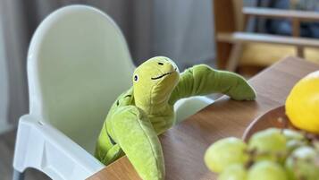 Un ranocchio di peluche verde su un tavolo di legno con una ciotola di uva verde.