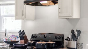 Una cocina con armarios blancos, una estufa negra y una encimera de granito.