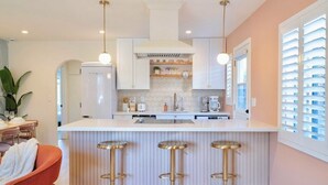 A modern kitchen with white cabinets, a central island with stools, and pendant lighting.