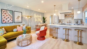 A modern kitchen with a bar area, a sofa, and a red chair.
