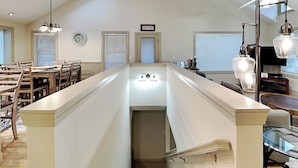 A modern kitchen with a central island, a dining area with wooden chairs, and a staircase leading to an upper level. - Beautiful Day by Taylor Made Deep Creek (McHenry)