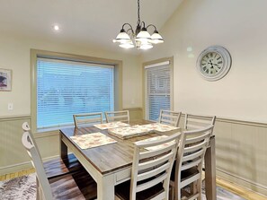 A dining area with a wooden table, white chairs, and a chandelier. - Beautiful Day by Taylor Made Deep Creek (McHenry)