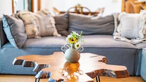 A modern living room with a grey sofa, a wooden coffee table, and a vase with flowers.