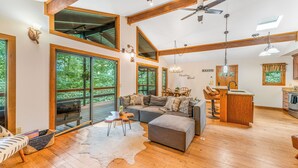 A spacious living room with a large sectional sofa, a dining area with a wooden table and chairs, and a kitchen with a countertop and cabinets.