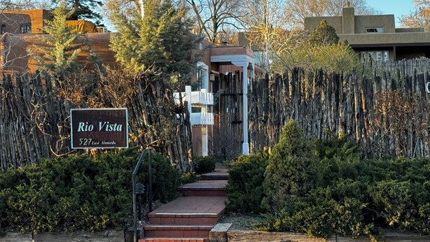 A sign for Rio Vista at 527 East Alameda, with a wooden fence and steps leading to a building. - Rustic charm meets comfort—king bed, AC, patio, walk 5 mins Canyon Rd, and Plaza (Santa Fe)