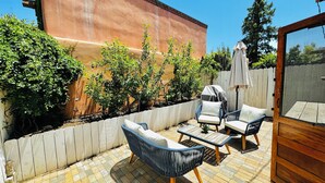 A patio with outdoor furniture, a white fence, and a wooden wall. - Rustic charm meets comfort—king bed, AC, patio, walk 5 mins Canyon Rd, and Plaza (Santa Fe)