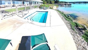 A hotel with a pool, outdoor seating, and a view of the water. - Dollhouse #4 at Portage Point Resort (Onekama)