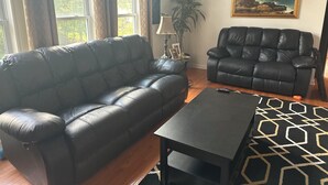 Ein Wohnzimmer mit zwei schwarzen Ledersofas, einem kleinen Tisch und einem Gemälde an der Wand.