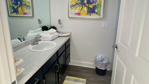 A bathroom with a sink, mirror, and two framed abstract paintings.