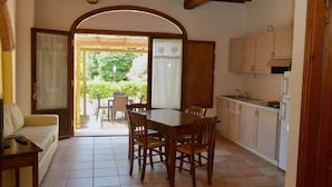 A kitchen with a dining table and chairs, a sofa, and a view of the outdoors. - Two-room apartment of about 45 square meters with air conditioning and heating, tastefully furnished and composed of a living room with equipped kitchenette and sofa bed, bedroom with double bed and bathroom with shower and bidet.Located on the ground fl (Riparbella)