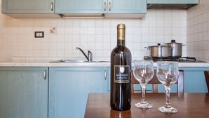 A kitchen with light blue cabinets, a wine bottle, and two wine glasses on a wooden table. - Two-room apartment of about 45 square meters with air conditioning and heating, tastefully furnished and composed of a living room with equipped kitchenette and sofa bed, bedroom with double bed and bathroom with shower and bidet.Located on the ground fl (Riparbella)