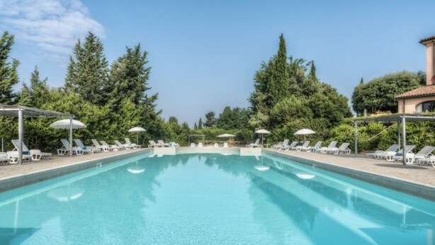 A rectangular swimming pool with lounge chairs and umbrellas, surrounded by trees. - Two-room apartment of about 45 square meters with air conditioning and heating, tastefully furnished and composed of a living room with equipped kitchenette and sofa bed, bedroom with double bed and bathroom with shower and bidet.Located on the ground fl (Riparbella)