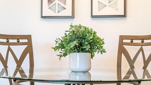 A round glass table with a white ceramic pot containing green foliage, flanked by two wooden chairs with a geometric design. - Connect With Nature at This Beautiful Urban Farm (Mesa)