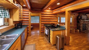 A log cabin interior with a kitchen featuring wooden cabinets, a stove, and a sink. - Mountain Getaway Cabin steps from Dwtn. W.P.: Hike, Bike, Fish & Enjoy 338570 (Woodland Park)
