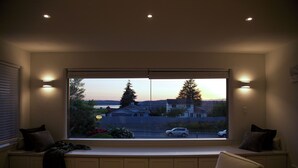 Una habitación con un amplio asiento junto a la ventana con vistas a una calle al atardecer.