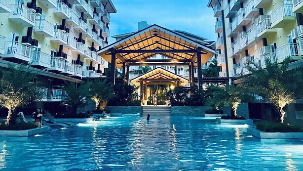 Un hotel con un atrium central, piscina y varios balcones.