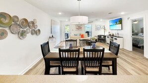 Een moderne eetruimte met een houten tafel en stoelen, een keuken op de achtergrond en decoratieve borden aan de muur.