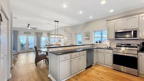 A modern kitchen with white cabinets, stainless steel appliances, and a wooden floor. - DuneFine Cape San Blas Sleeps 10 & Dog Friendly Private Pool (Cape San Blas)