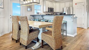 A modern kitchen with white cabinetry, stainless steel appliances, and a central island with bar stools. - DuneFine Cape San Blas Sleeps 10 & Dog Friendly Private Pool (Cape San Blas)