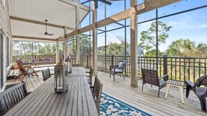 A covered outdoor deck with wooden furniture and a patterned rug. - Charming Beachfront Beach House/2BR/Loft/Sleeps 8 (Cape San Blas)