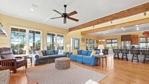 A spacious living room with a large sectional sofa, a wooden coffee table, and a dining area with a table and chairs. - Charming Beachfront Beach House/2BR/Loft/Sleeps 8 (Cape San Blas)