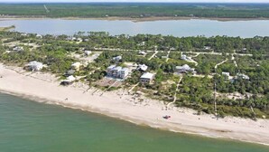An aerial view of a coastal property with multiple buildings, a beach, and a large body of water. - Charming Beachfront Beach House/2BR/Loft/Sleeps 8 (Cape San Blas)