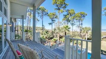 A wooden deck with a pool, surrounded by trees and a clear view of the ocean.