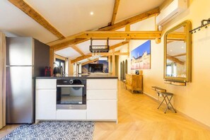 Une cuisine moderne dotée d’un îlot central, de poutres en bois et d’un grand miroir.