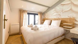 Quarto de hotel moderno com uma cama grande, uma escrivaninha e uma janela com cortinas.