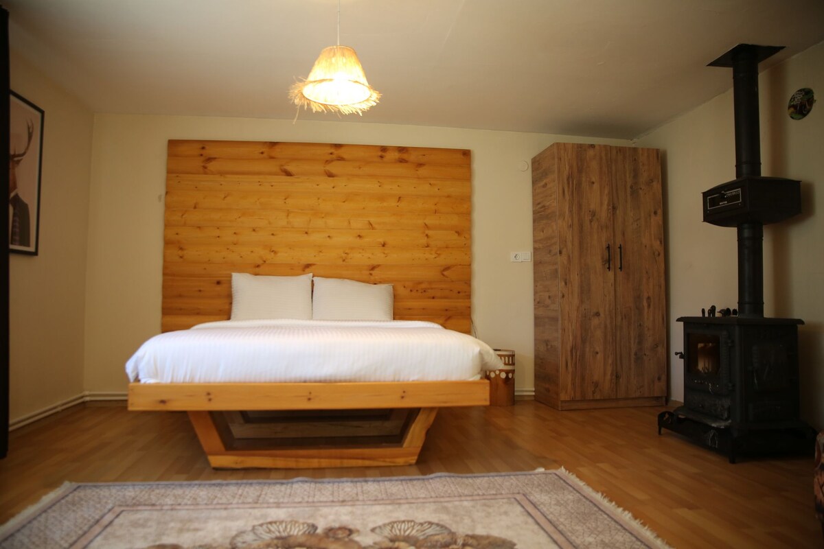 A bedroom with a wooden headboard, a bed, a wardrobe, and a wood-burning stove.