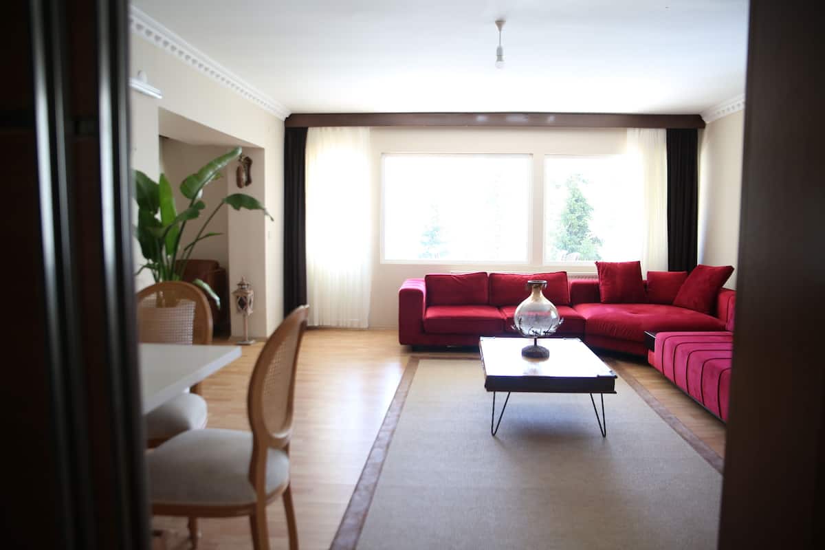 Una sala de estar con un sofá rojo, una mesa de centro y un comedor con mesa y sillas.
