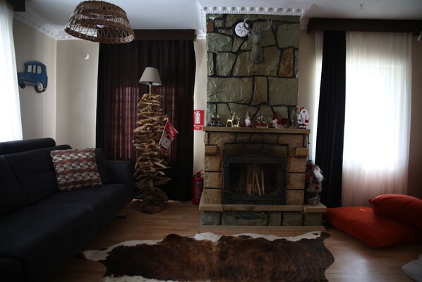 A living room with a stone fireplace, a blue toy car on the wall, a sofa, a red chair, and a cowhide rug. - Abant Luna (Bolu)