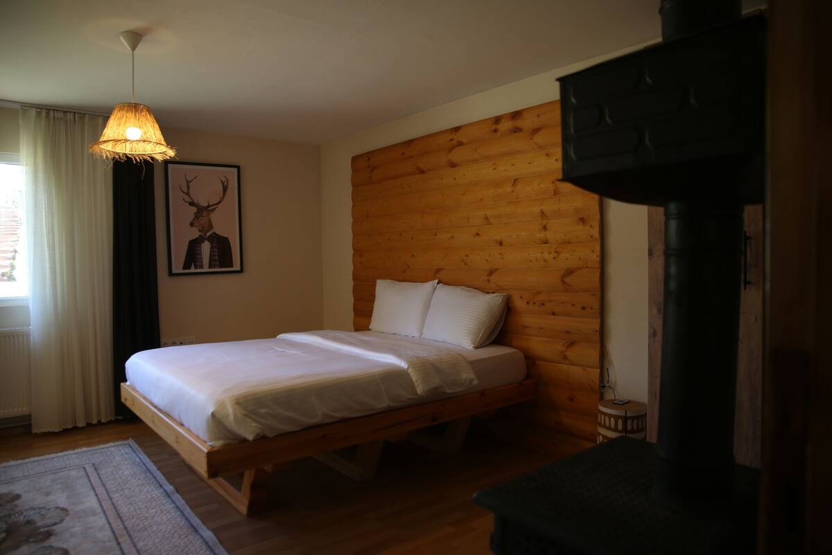 Una cama de madera en una habitación con cabecera de madera, una lámpara colgante y un cuadro enmarcado en la pared.