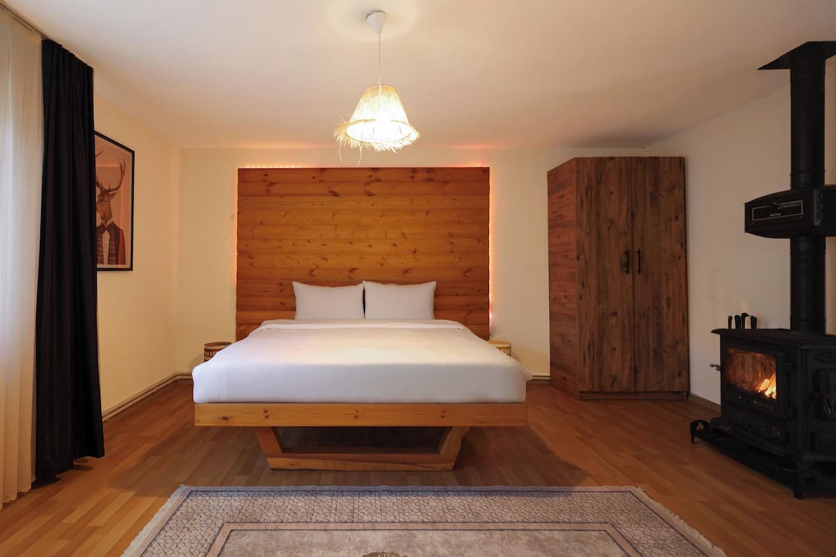 Un dormitorio con cama, cabecera de madera, chimenea y lámpara colgante.